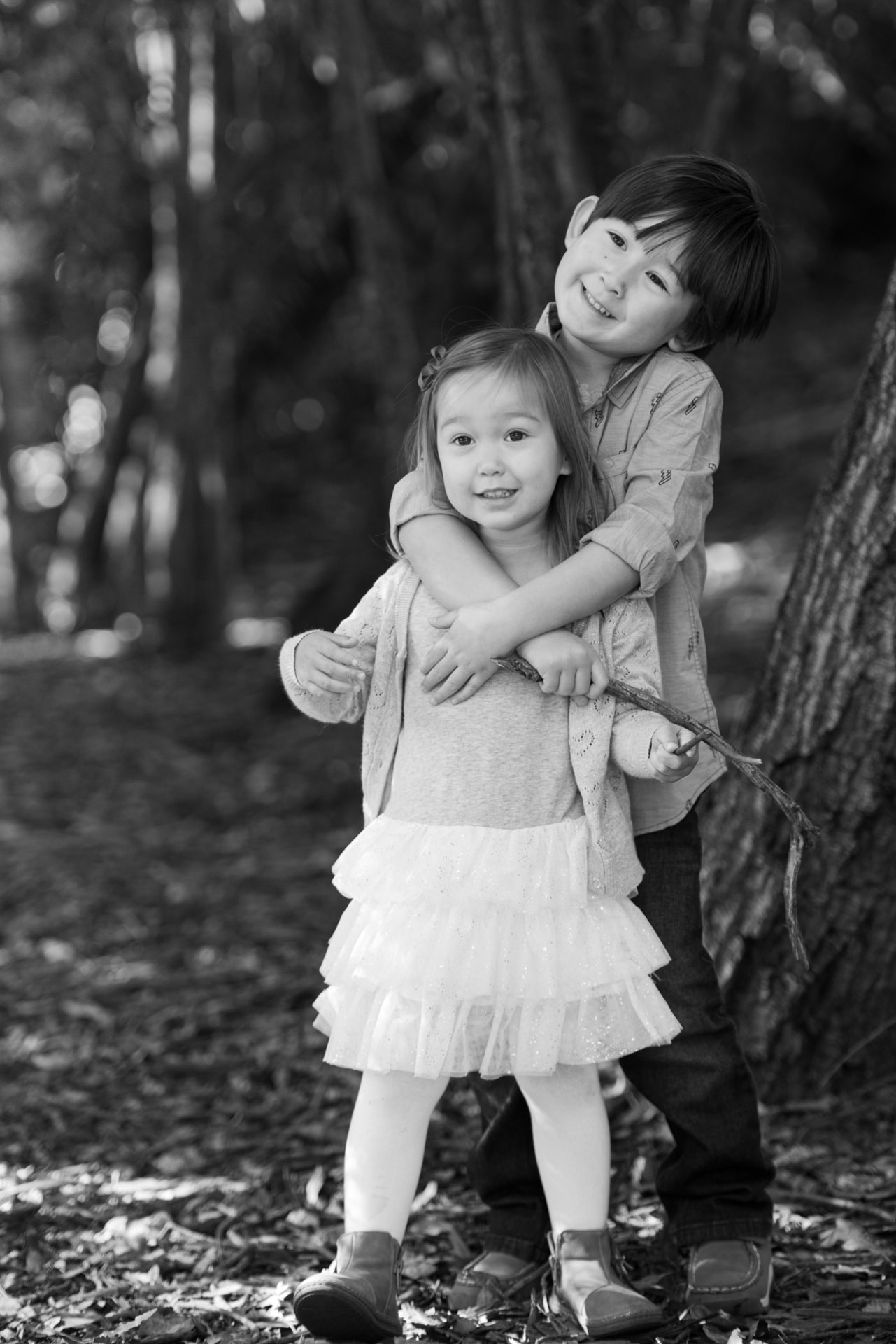 Big brother wrapping his sister in a hug among the trees