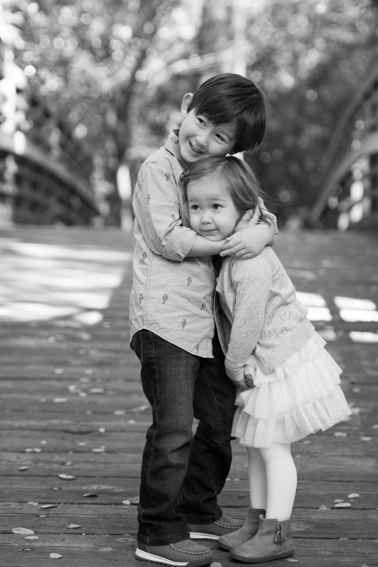 Siblings holding each other on a wooden footbridge